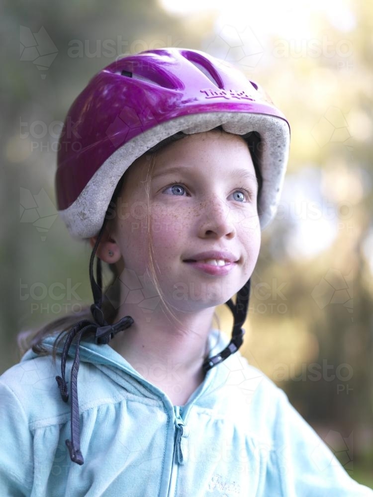 Young girl in purple helmet preparing to go bike riding - Australian Stock Image