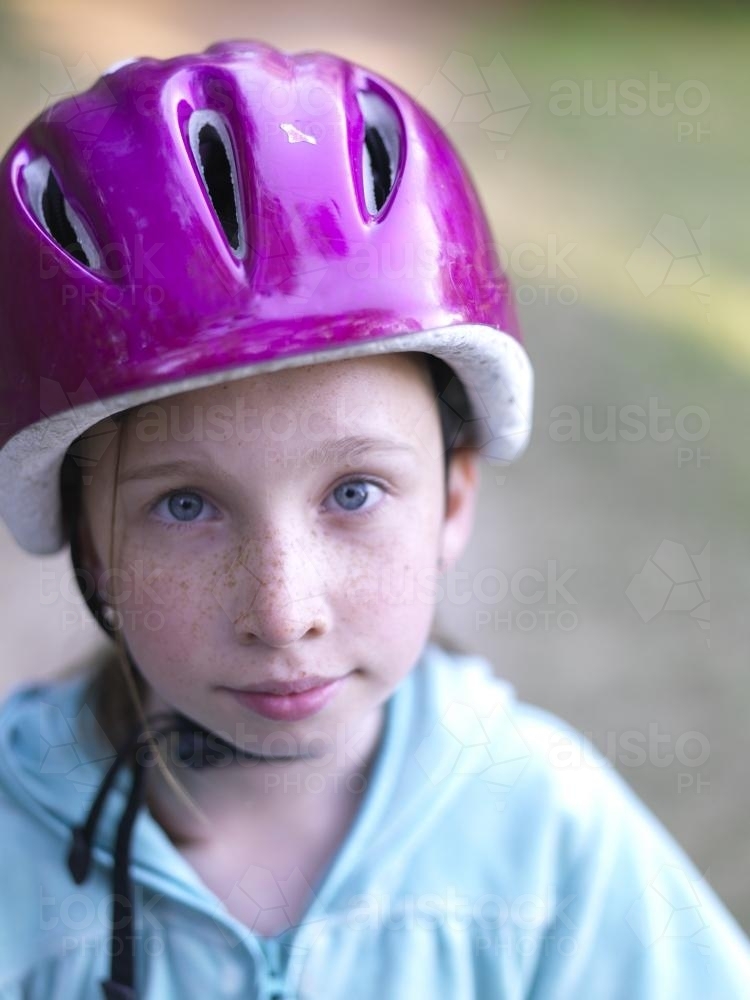 Young girl in purple helmet preparing to go bike riding - Australian Stock Image