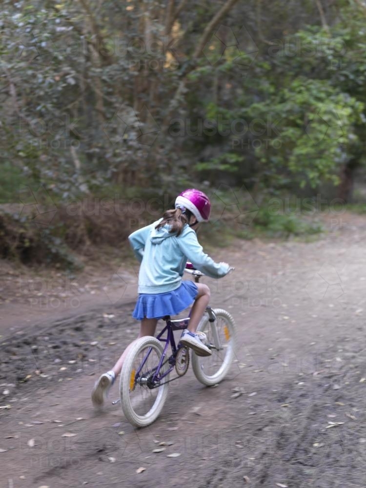 Young girl in purple helmet riding bike on bush track - Australian Stock Image
