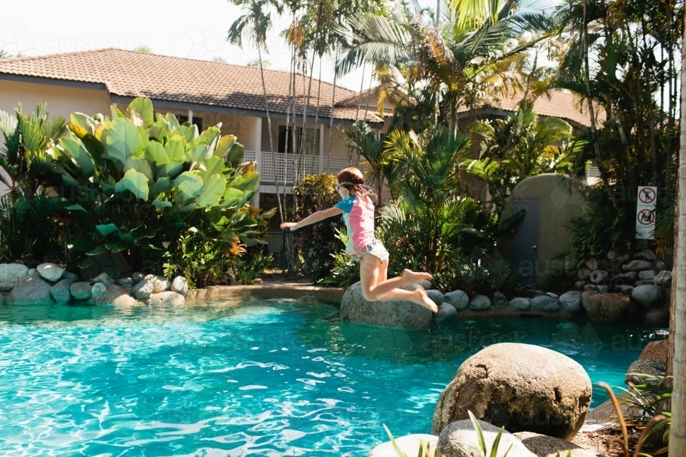 Young girl jumping into a pool - Australian Stock Image