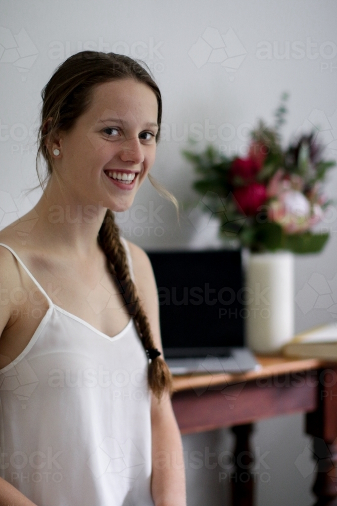 Young girl laughing inside in front of work desk - Australian Stock Image