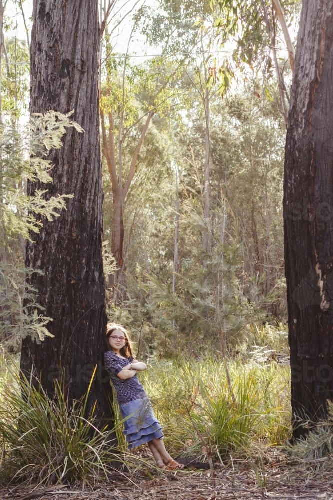 Young girl leaning against large tree - Australian Stock Image