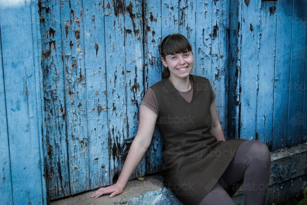 image of young girl leaning against old blue door with