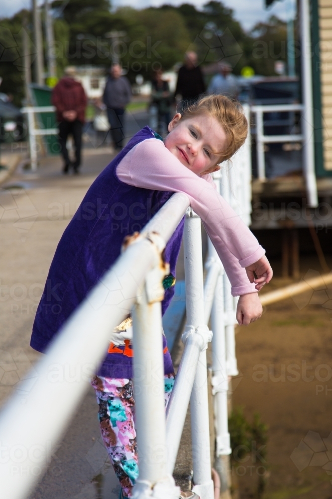Young girl leaning on a railing at a pier - Australian Stock Image