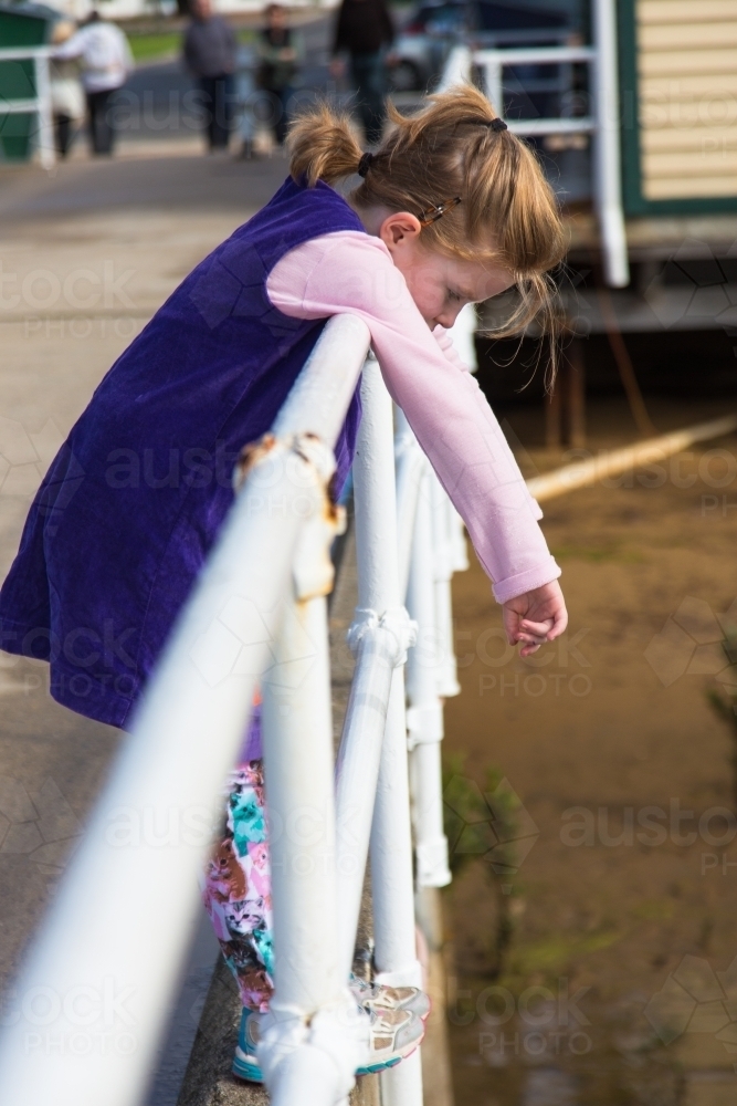 Young girl leaning on a railing at a pier - Australian Stock Image