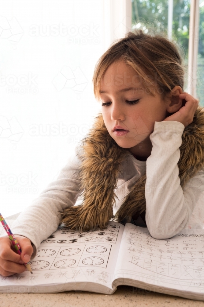 Young girl learning her clock times. - Australian Stock Image