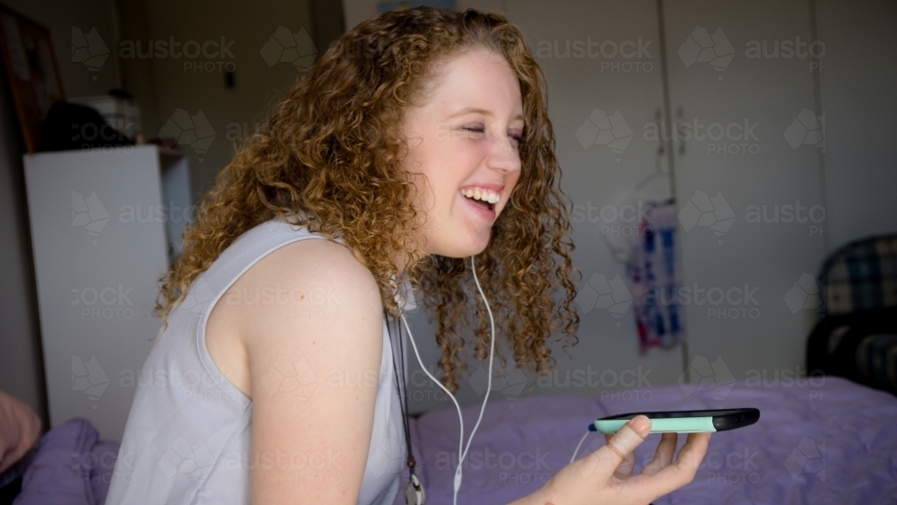 Young girl listening to music from mobile phone - Australian Stock Image