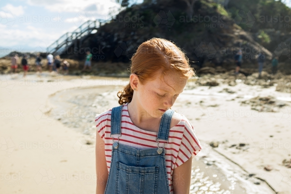 Young girl looking down at the beach - Australian Stock Image