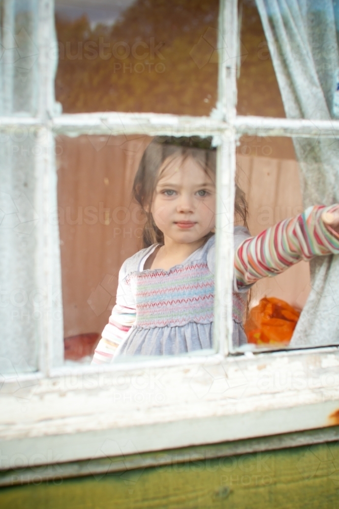 Young girl looking out cubby house window - Australian Stock Image