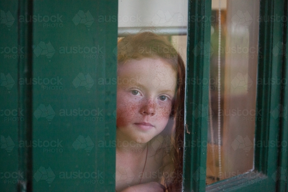 Young girl looking out of a window - Australian Stock Image