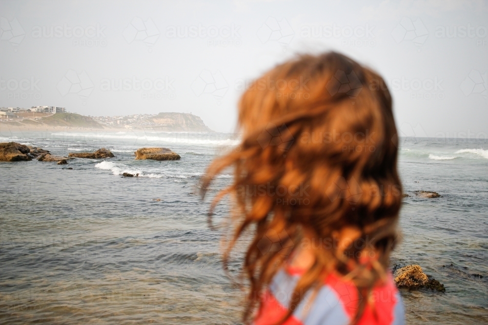 Young girl looking out to the ocean on an overcast day - Australian Stock Image