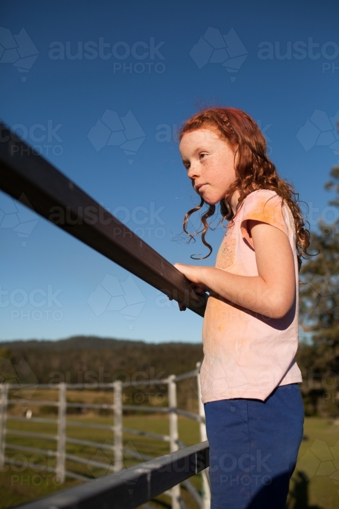 Young girl looking over a metal fence - Australian Stock Image