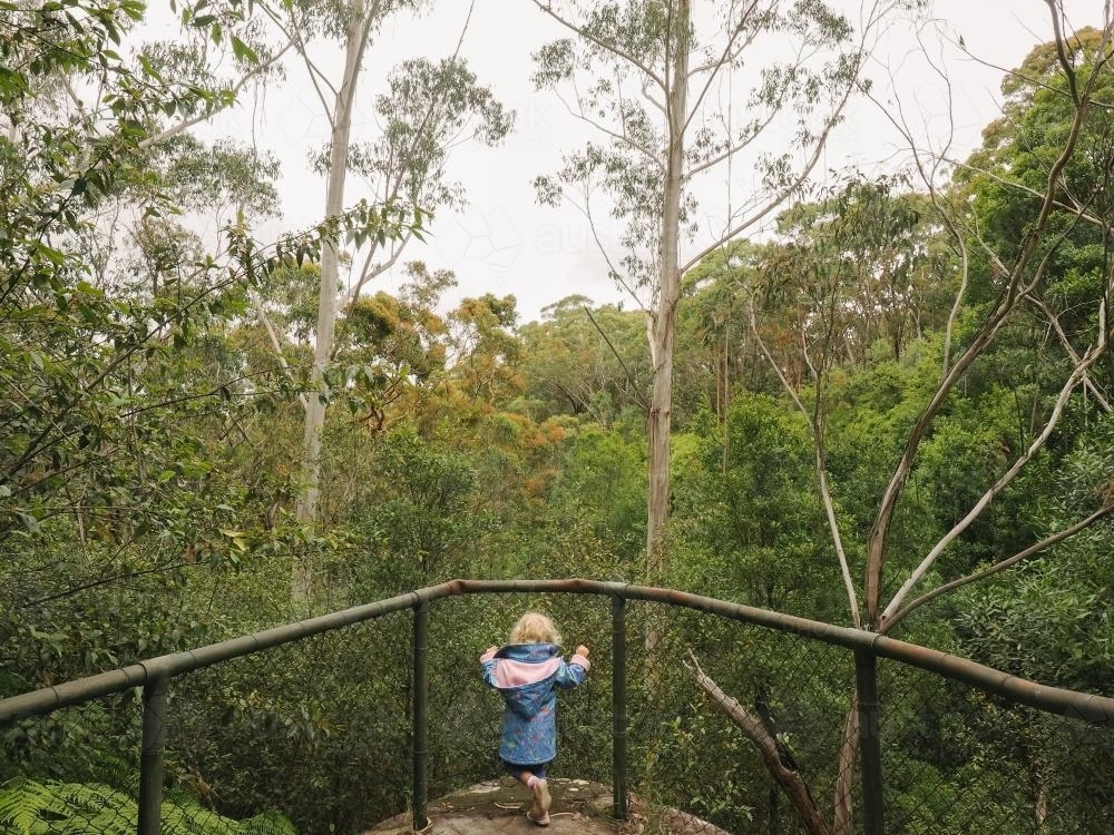 Young girl looking through fence at a lookout - Australian Stock Image