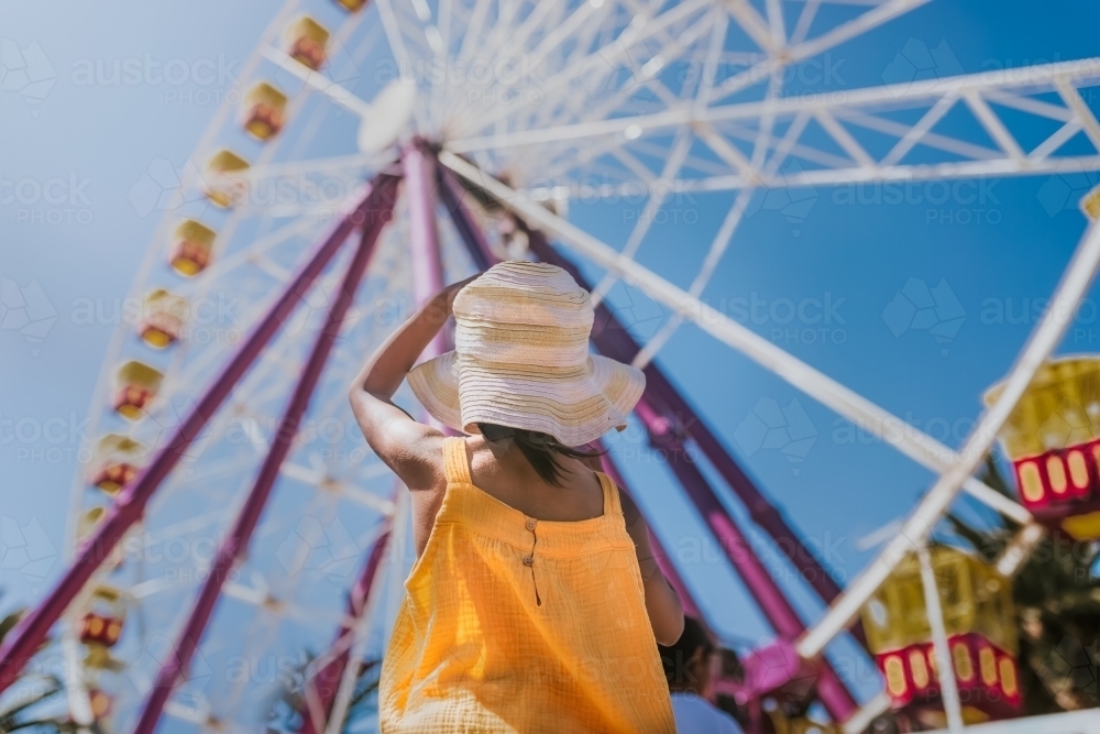 Young girl looking up at Ferris wheel - Australian Stock Image