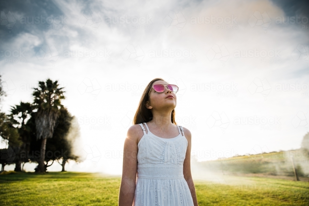Young girl looking up at the cloudy sky - Australian Stock Image