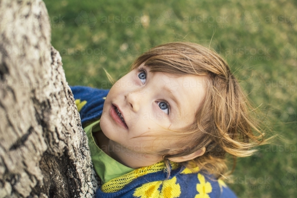 Young girl looking up at tree - Australian Stock Image