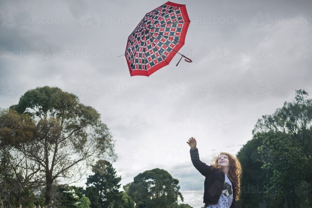 Young girl losing her umbrella on a windy winter day - Australian Stock Image
