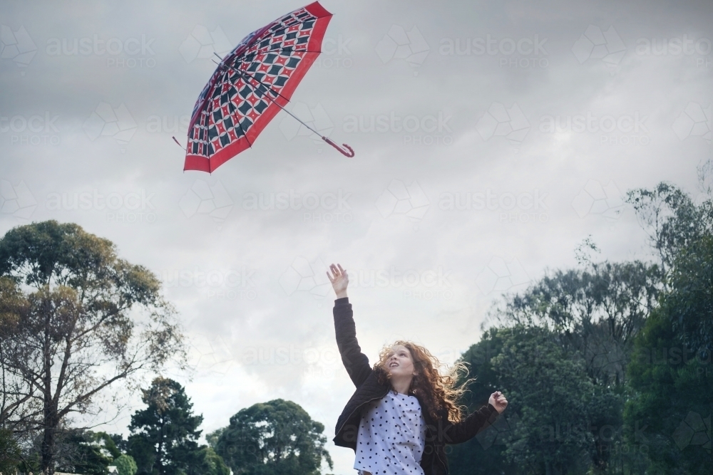 Young girl losing her umbrella on a windy winter day - Australian Stock Image