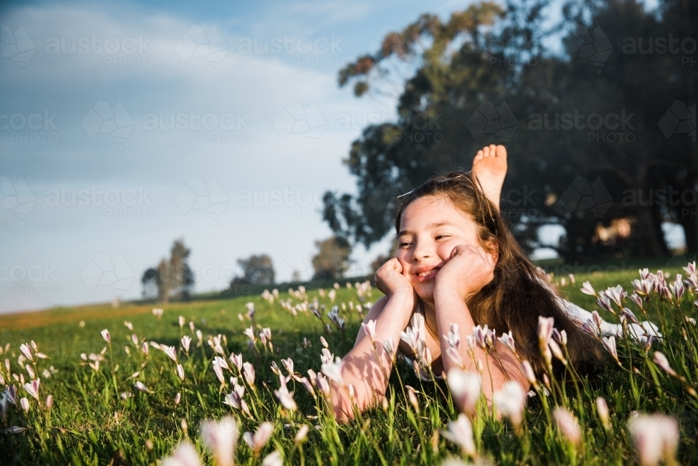 Young girl lying in field of flowers - Australian Stock Image