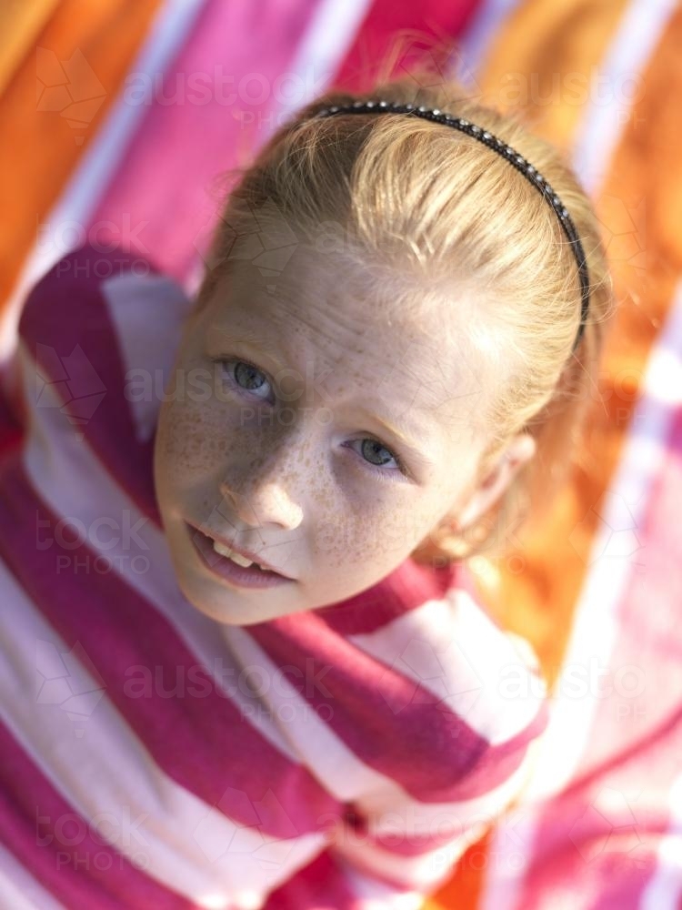 Young girl lying on stripy towel - Australian Stock Image