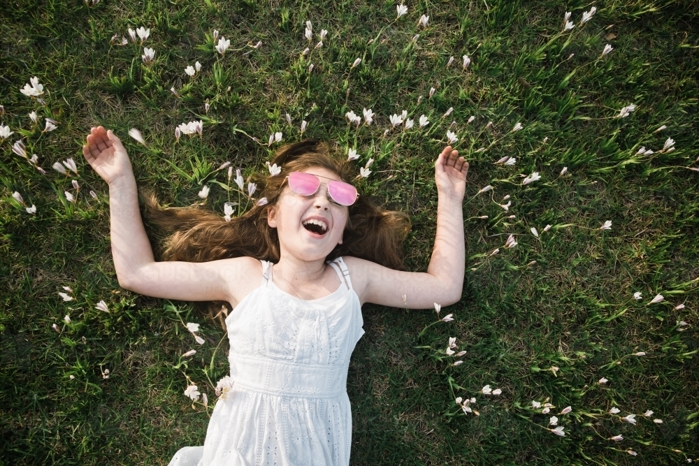 Young girl lying on the grass, laughing - Australian Stock Image