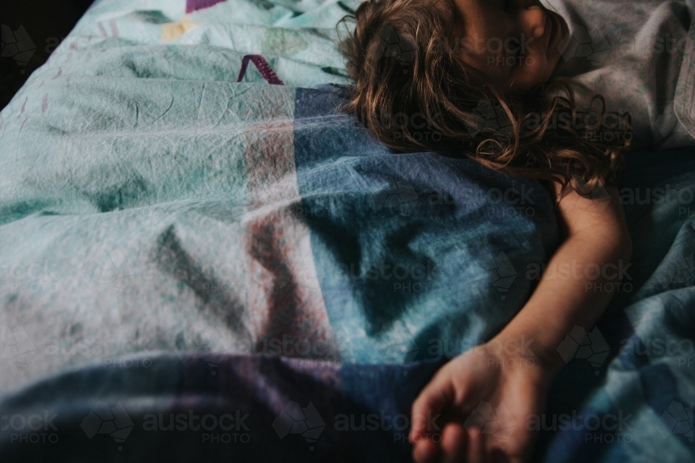 Young girl lying quietly on bed - Australian Stock Image
