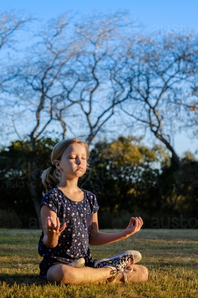 Young girl meditating in the park - Australian Stock Image