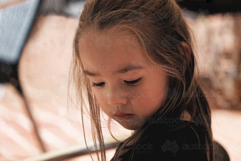 Young girl of mixed race looking down deep in thoughts - Australian Stock Image