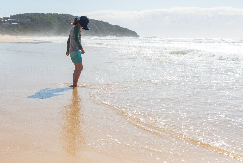 Image of Young girl on a beach looking at the sea - Austockphoto