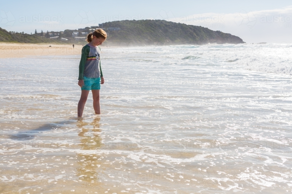 Young girl on a beach looking at the sea - Australian Stock Image