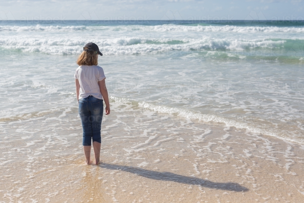 Young girl on a beach looking out to sea - Australian Stock Image