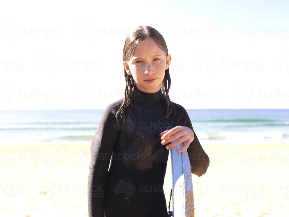 Young girl on beach in wetsuit with body board - Australian Stock Image