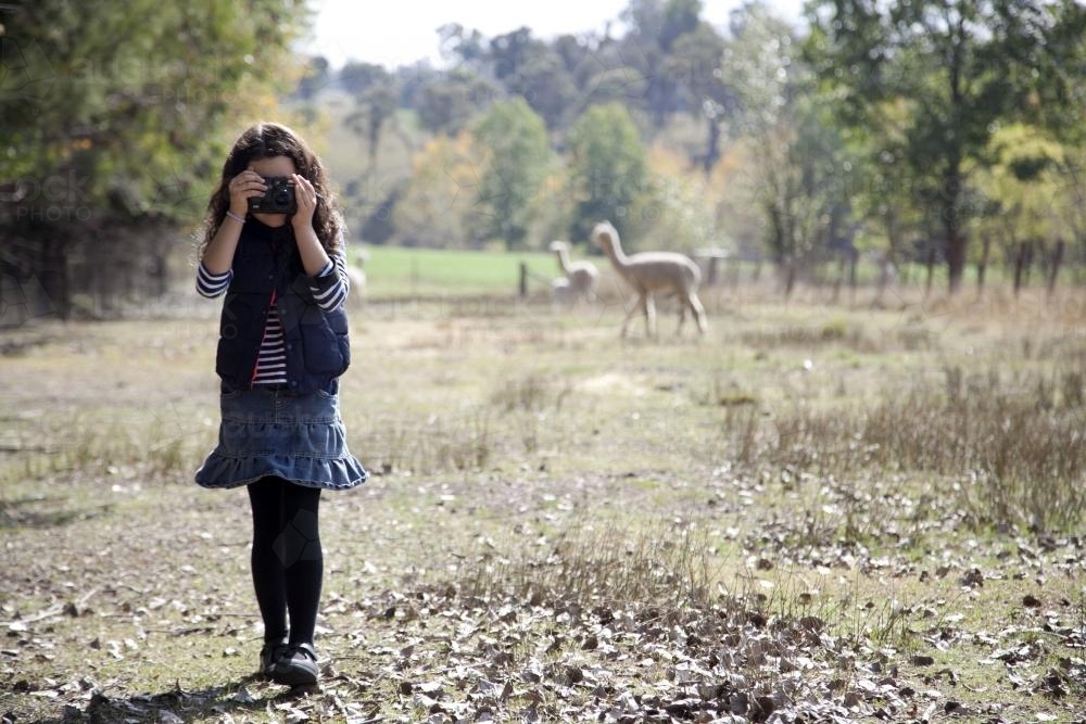 Young girl outside on a farm using a digital camera - Australian Stock Image