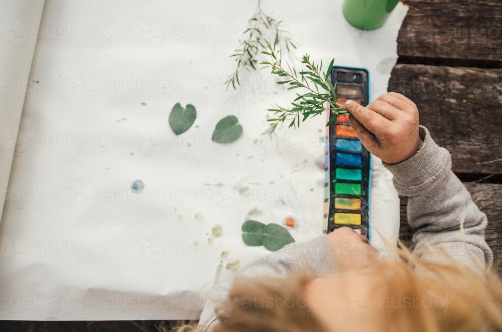 Young girl painting with leaves - Australian Stock Image