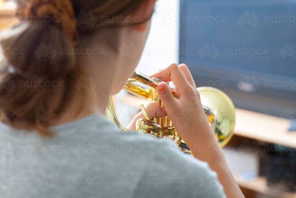 Young girl performing trumpet practice at home - Australian Stock Image
