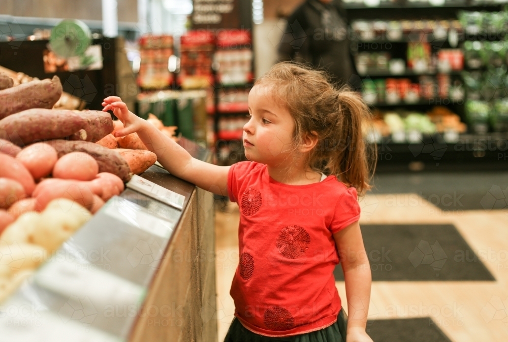 Young Girl Picking Potatoes in Supermarket - Australian Stock Image