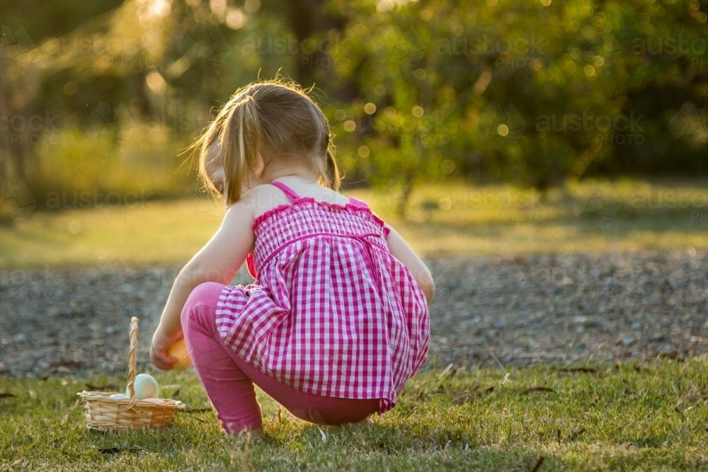 Young girl placing Easter eggs in a basket - Australian Stock Image