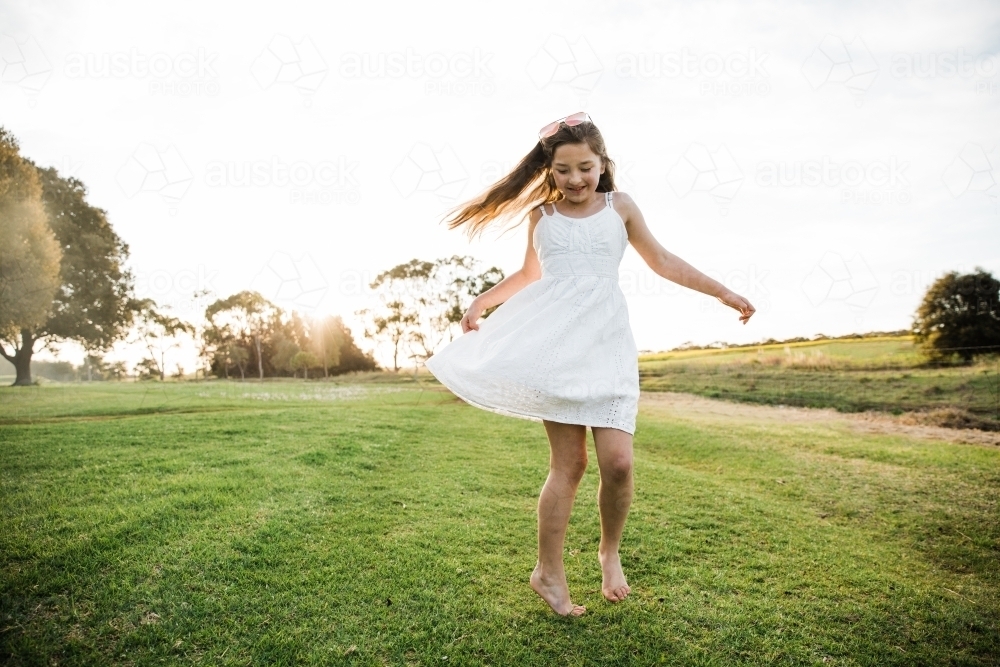 Young girl playing in a field in the sunshine - Australian Stock Image