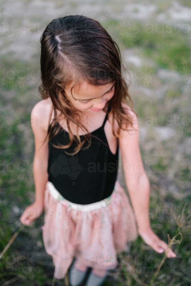 Young girl playing in a field picking flowers - Australian Stock Image