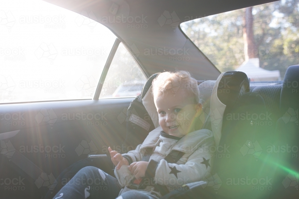 Young girl playing in her car seat in the afternoon sun - Australian Stock Image