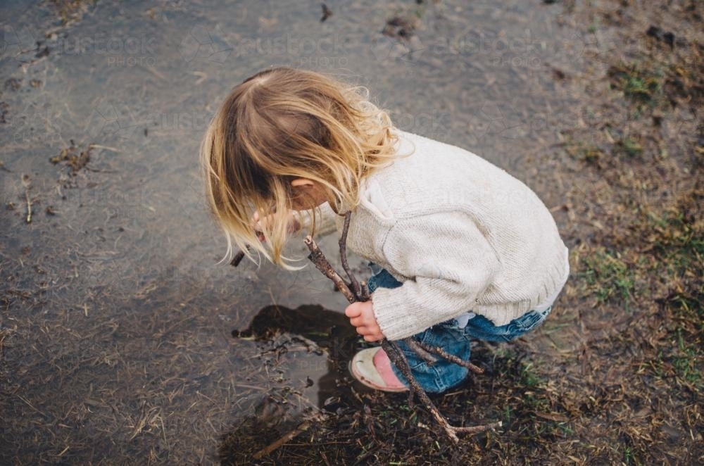 Young girl playing in puddle - Australian Stock Image
