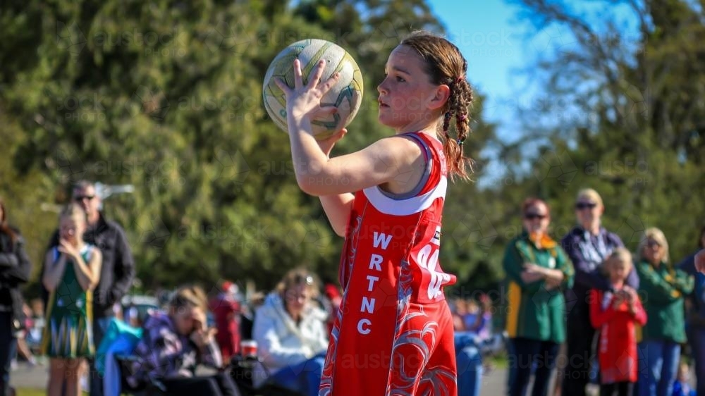 Young girl playing netball catching a ball - Australian Stock Image