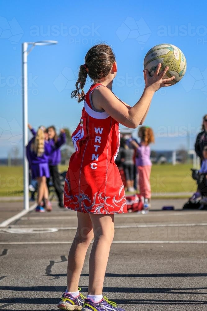 Young girl playing netball passing a ball - Australian Stock Image