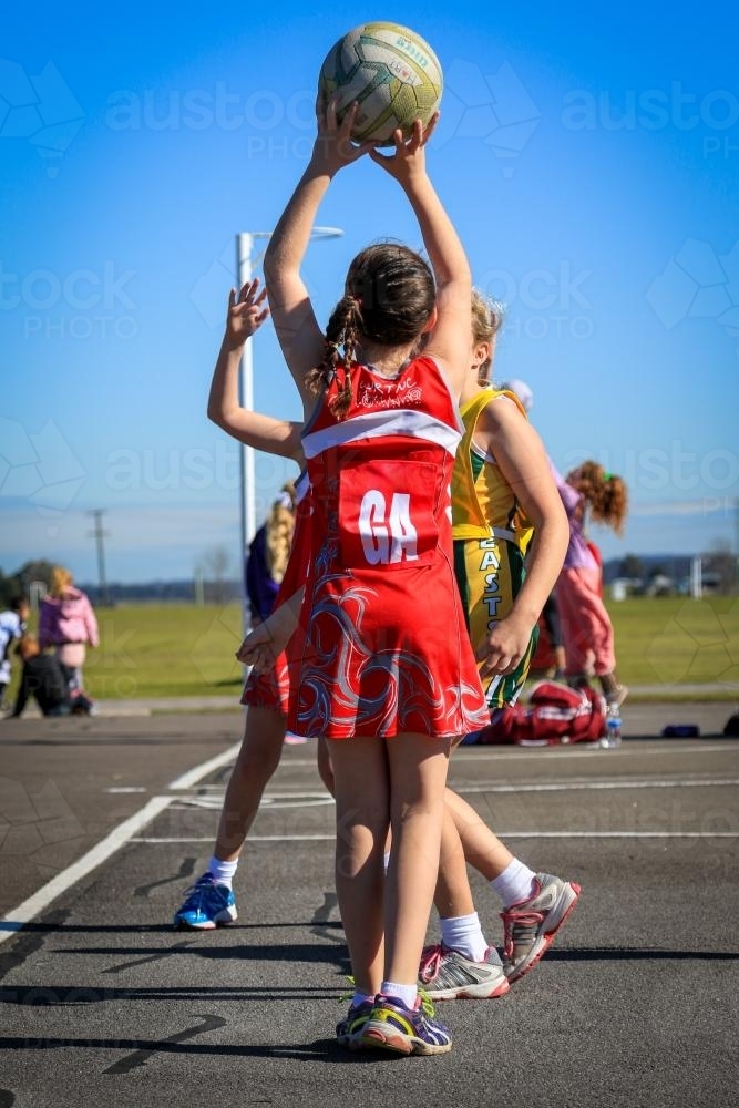 Young girl playing netball shooting for goal - Australian Stock Image
