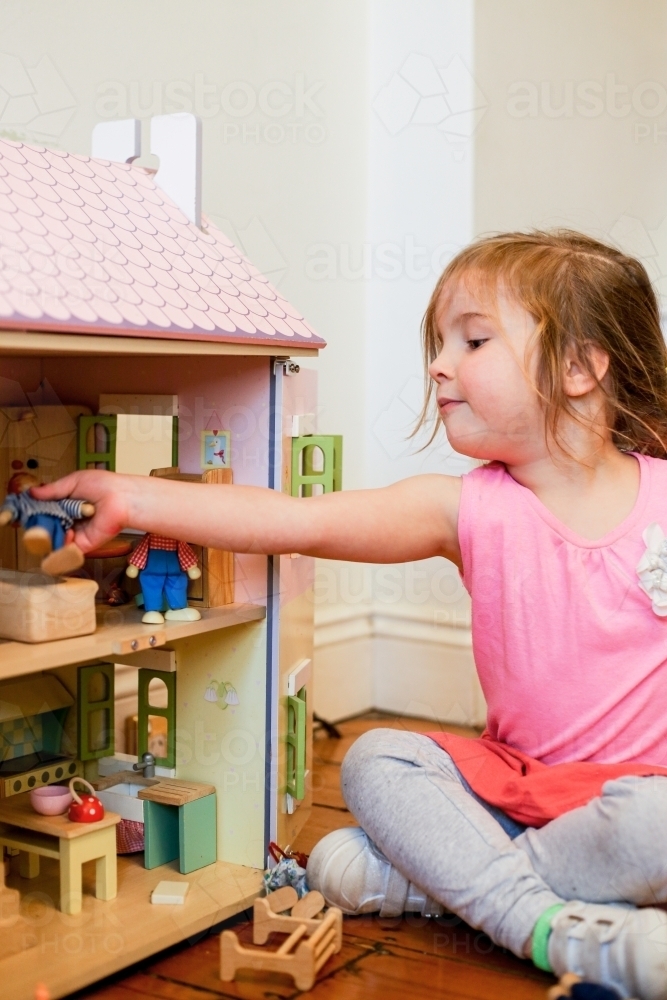 Image of Young girl playing with a dollhouse Austockphoto