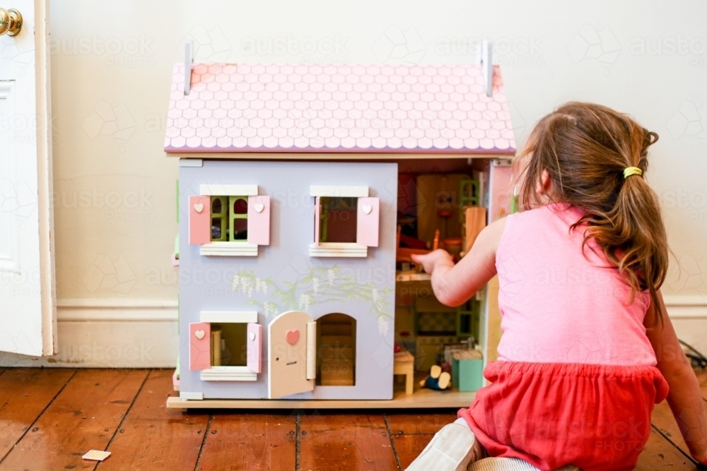 Young girl playing with a dollhouse - Australian Stock Image