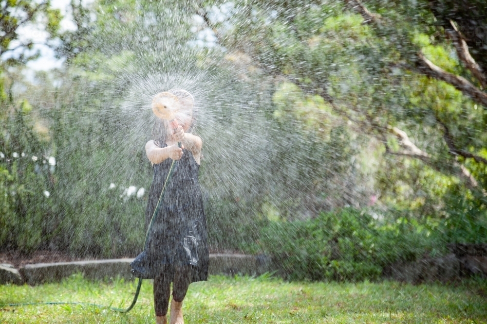 Young girl playing with sprinkler in summer - Australian Stock Image