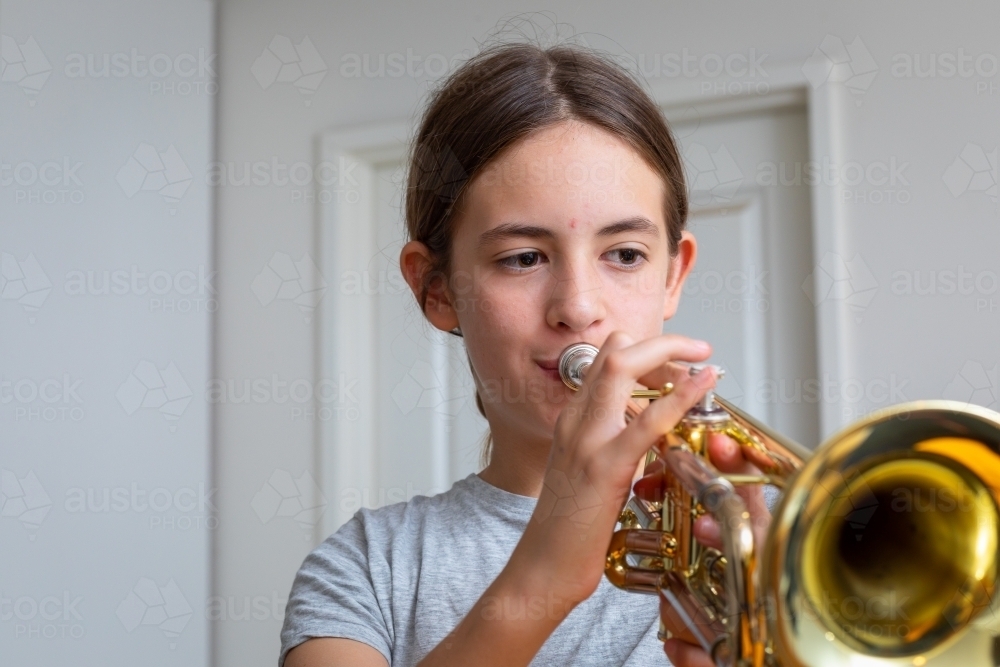 young girl practising her trumpet at home - Australian Stock Image