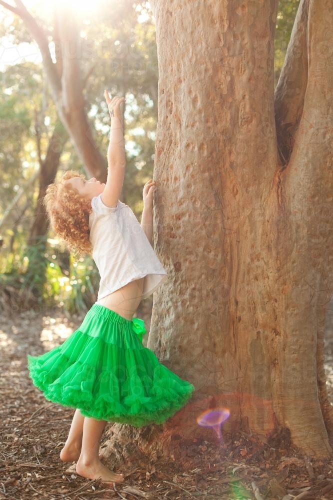Young girl reaching up wearing a green tutu skirt - Australian Stock Image