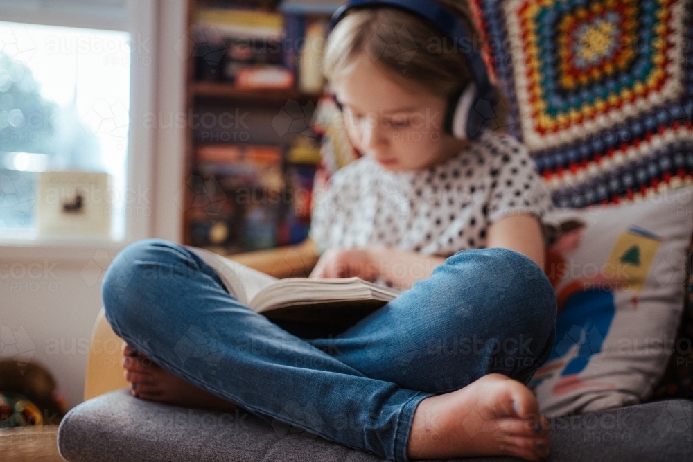 Young girl reading a book at home - Australian Stock Image